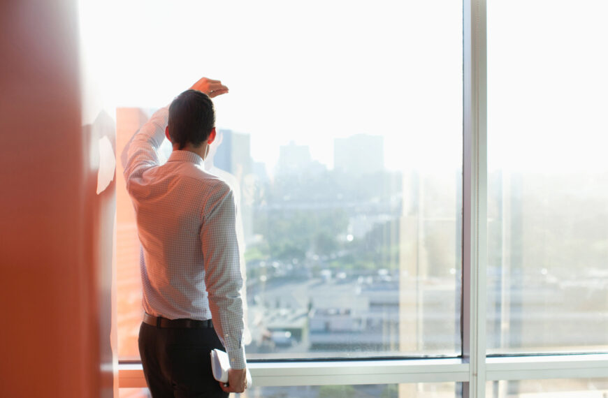 Man leans against a window and looks at the view