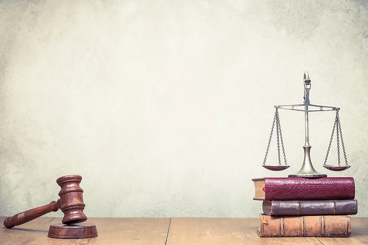 A gavel and a scale on top of some books on a table.